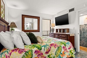 Ein Schlafzimmer mit einem Bett, einem Schminktisch, einem Spiegel und einem Fernseher.