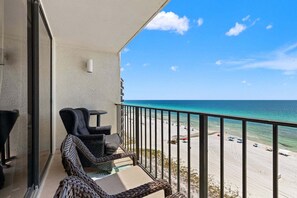 A balcony with wicker furniture overlooking a beach.