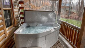 A hot tub on a wooden deck with a view of trees and a grassy area.