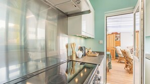 Una cocina moderna con estufa de acero inoxidable, utensilios de madera y una cesta de mimbre sobre la encimera.