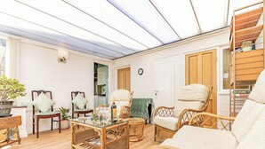 Una sala de estar acogedora con muebles de mimbre, una mesa de centro de vidrio y una planta en maceta.