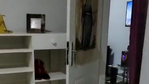 A room with a white door leading to a hallway. There is a shoe rack with multiple shelves, some shoes are visible. A small framed picture hangs on the wall above the door. - Luxury apartment in the center of Abidjan (Abidjan)