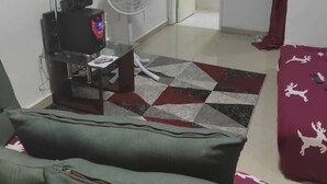 A living room with a television, a fan, a sofa, and a patterned rug. - Luxury apartment in the center of Abidjan (Abidjan)