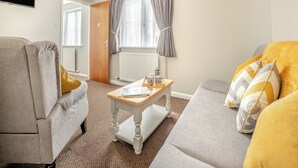 Un salon avec un canapé, une table basse et un téléviseur.