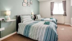 Une chambre avec deux lits, une fenêtre avec des rideaux, un radiateur et des lampes fixées au mur.