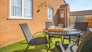 Une terrasse avec une table ronde, des chaises et un plateau contenant des tasses et un livre.