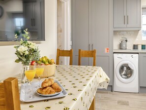 A dining area with a table set for breakfast, including croissants, fruit, and juice.