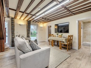 A modern living room with a sofa, dining table, and a TV. - Two Chainbridge Barns (Skegness)