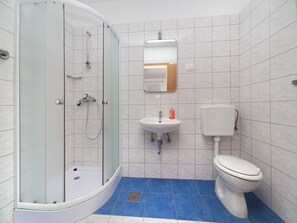 Enjoy a refreshing shower in the bathroom, featuring a glass-enclosed shower with handheld showerheads and a pedestal sink.