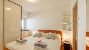 Un lit bien fait, avec des serviettes pliées, une table de chevet avec une lampe et un miroir au-dessus du lit.