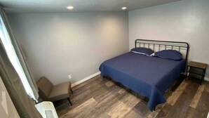 Ein Schlafzimmer mit einem Bett, einem Sessel und einem kleinen Tisch.