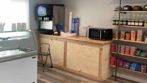 Eine Küchenzeile mit Kühlschrank, Mikrowelle und Regalen mit verpackten Lebensmitteln.