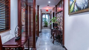 A hallway with wooden slats, a decorative wall with a peacock painting, and a red lantern. - Jingshan Hotel (Haikou)