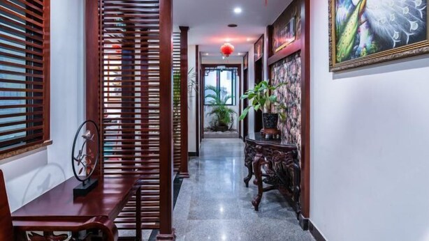 A hallway with wooden slats, a decorative wall with a peacock painting, and a red lantern. - Jingshan Hotel (Haikou)