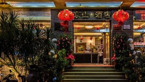 A hotel entrance with a signboard, steps leading up to the entrance, and red lanterns. - Jingshan Hotel (Haikou)