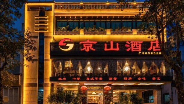 A hotel with a prominent sign, a balcony, and a well-lit entrance. - Jingshan Hotel (Haikou)