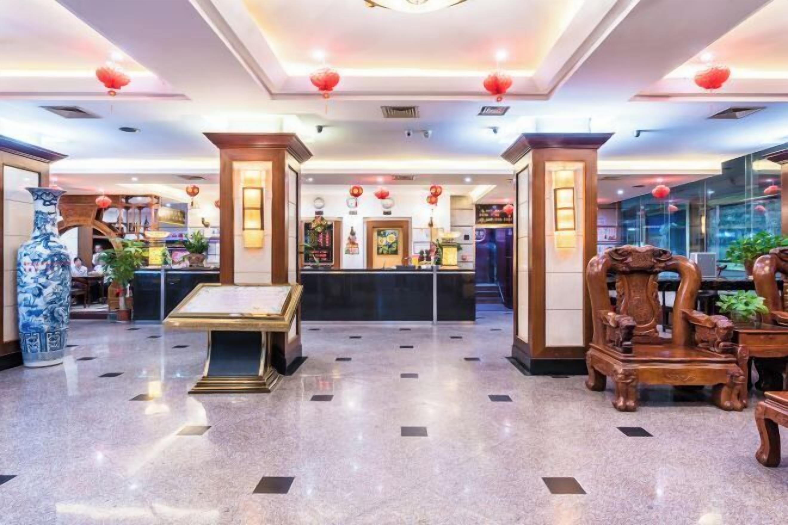 Un hall d’hôtel avec un comptoir d’accueil, des meubles en bois de style traditionnel et des lanternes rouges.