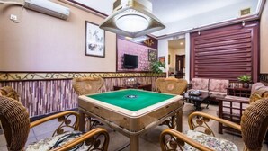 A room with a pool table, wicker chairs, a television, and a large window with blinds. - Jingshan Hotel (Haikou)