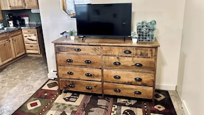 Una cocina con armarios de madera, un televisor negro sobre un aparador de madera y una alfombra estampada.