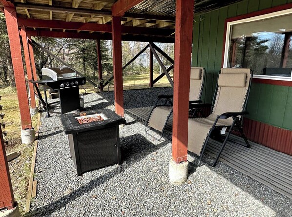 An outdoor patio with a grill, seating, and a covered area.