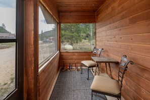 Cozy cabin with a rustic interior, featuring a table and chairs, and a large window offering views of the surrounding landscape.