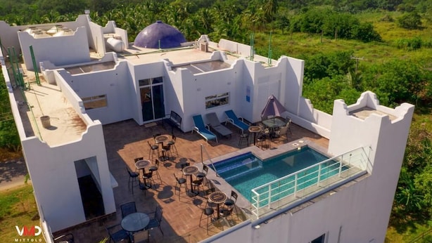 Un tetto con piscina, poltrone da relax e tavoli.