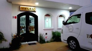 Un edificio con reception, una porta d'ingresso nera e un furgone bianco parcheggiato davanti.