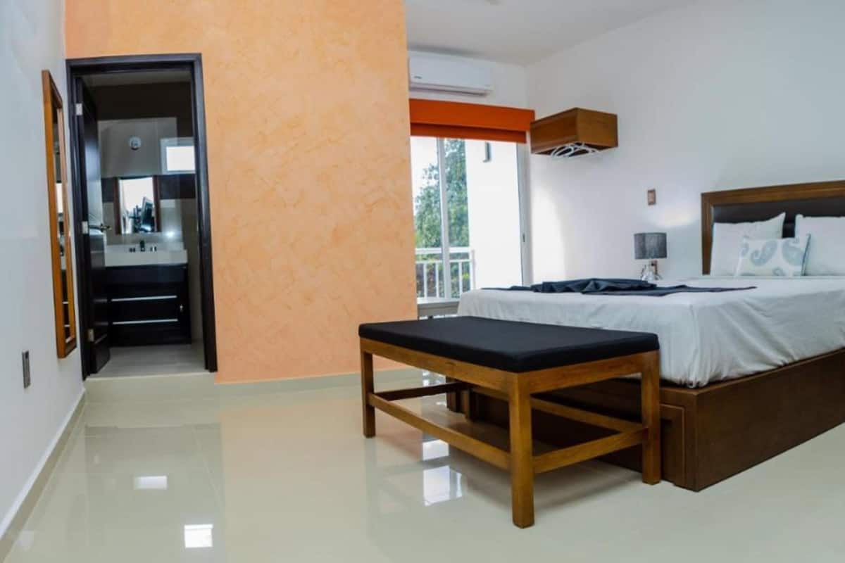 A bedroom with a bed, bench, and wardrobe.