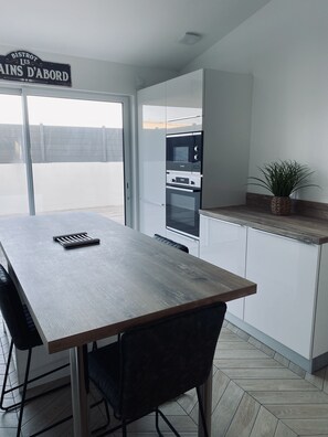 A modern kitchen with a wooden table, black chairs, and a built-in oven.