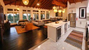 Amplia sala de estar con una isla grande, piso de madera oscura y un techo alto con vigas a la vista.