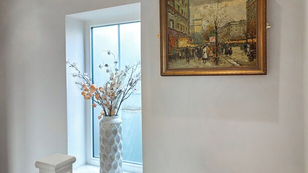 A room with a large window, a vase with branches, and a framed painting on the wall. - Sykes Head Cottage - UK42147 (Oakworth)