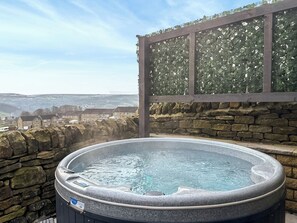 Een hottub op een balkon met een stenen muur en een uitzicht op huizen.