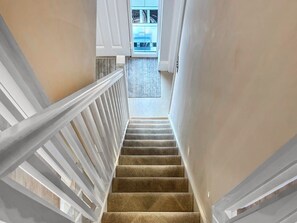 A carpeted staircase with white railings leading to a room with a view. - Sykes Head Cottage - UK42147 (Oakworth)
