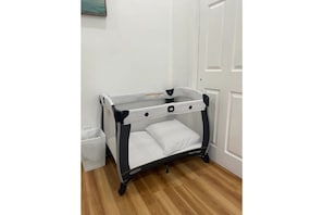 A portable crib with a mesh top and padded bottom, perfect for a comfortable sleeping space.