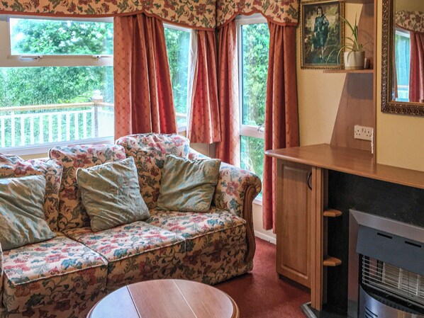A cozy living room with a floral sofa, a wooden cabinet, and a fireplace.