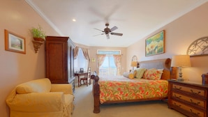 Une chambre à coucher comprenant un lit, une chaise, un bureau, une commode et un ventilateur de plafond.
