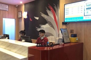A reception desk with a digital display, a clock, and a wall with a feather design. - Shankee Hotel (Xianyou Lizhong Pedestrian Street) (Xianyou)
