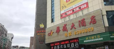 A building with multiple signs, including a prominent red sign with yellow text and a green sign with white text.