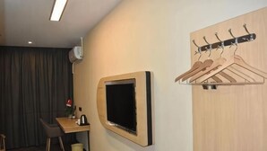 A hotel room with a desk, chair, TV, coat rack, and a wooden wardrobe. - Shankee Hotel (Xianyou Lizhong Pedestrian Street) (Xianyou)