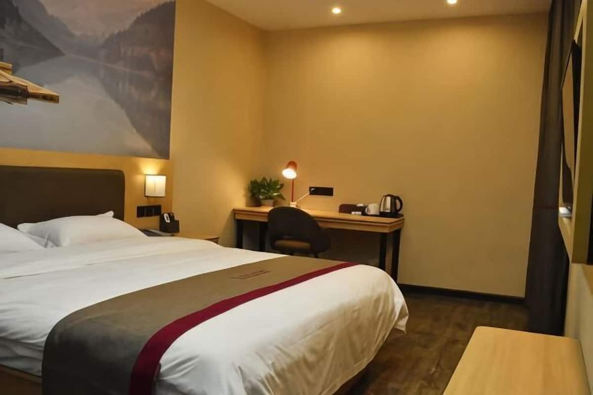 A hotel room with a bed, desk, chair, and a small table.