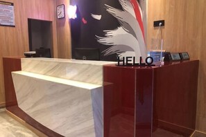 A reception desk with a marble counter, a 'HELLO' sign, and a wall-mounted clock. - Shankee Hotel (Xianyou Lizhong Pedestrian Street) (Xianyou)