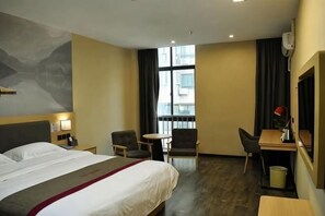 A hotel room with a bed, two chairs, a desk, a small table, a window with curtains, and a wall-mounted air conditioner. - Shankee Hotel (Xianyou Lizhong Pedestrian Street) (Xianyou)