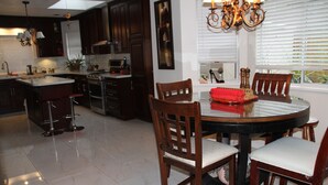 A modern kitchen with dark wood cabinets, a central island with stools, a dining table with chairs, and a chandelier. -  Large Comfy room w Private bath in gre (Richmond)