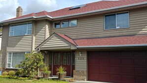 A two-story house with a red garage door, beige siding, and a brick chimney. -  Large Comfy room w Private bath in gre (Richmond)
