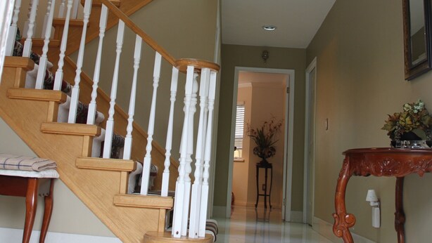 A grand staircase with white balusters and wooden steps, leading to a landing with a potted plant. -  Large Comfy room w Private bath in gre (Richmond)