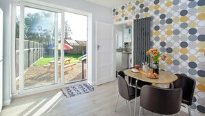 Una cocina moderna con un ventanal grande, una zona de comedor con mesa y sillas, y un muro con diseño.