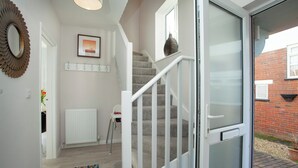 Una escalera con barandilla blanca que lleva a una puerta con paneles de vidrio esmerilado.