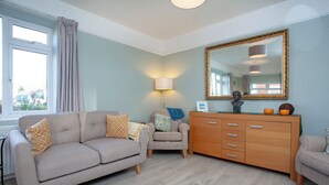 Una sala de estar con un sofá, un sillón y un aparador de madera.