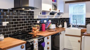 A modern kitchen with black and white tiled backsplash, stainless steel appliances, wooden countertops, and white cabinetry.