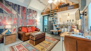 Quarto estilo loft com cama em mezzanine, escada de madeira e decoração rústica.